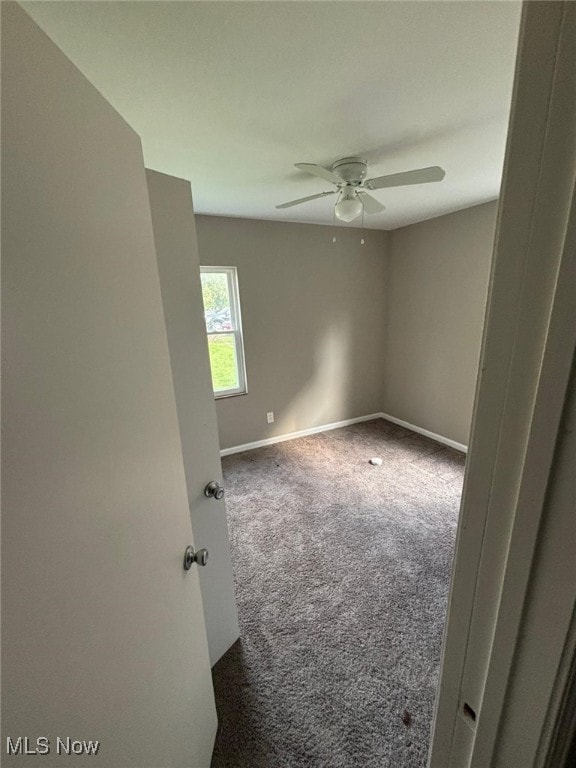 carpeted spare room with baseboards and ceiling fan