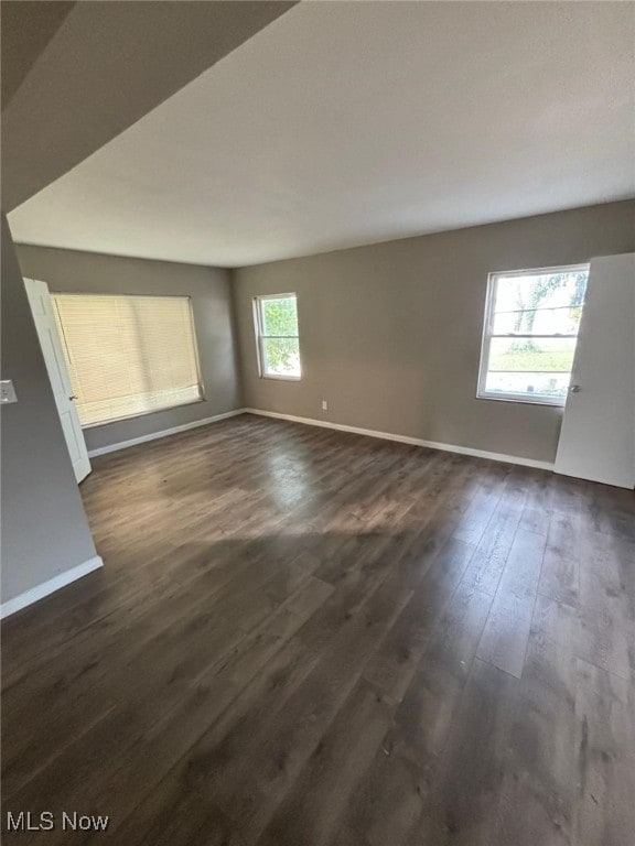 empty room featuring dark wood finished floors and baseboards