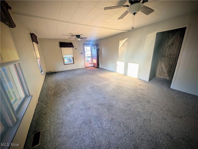 carpeted spare room featuring visible vents and ceiling fan