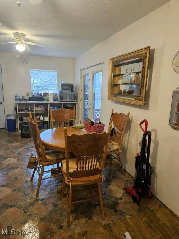 dining space with stone finish floor and a ceiling fan