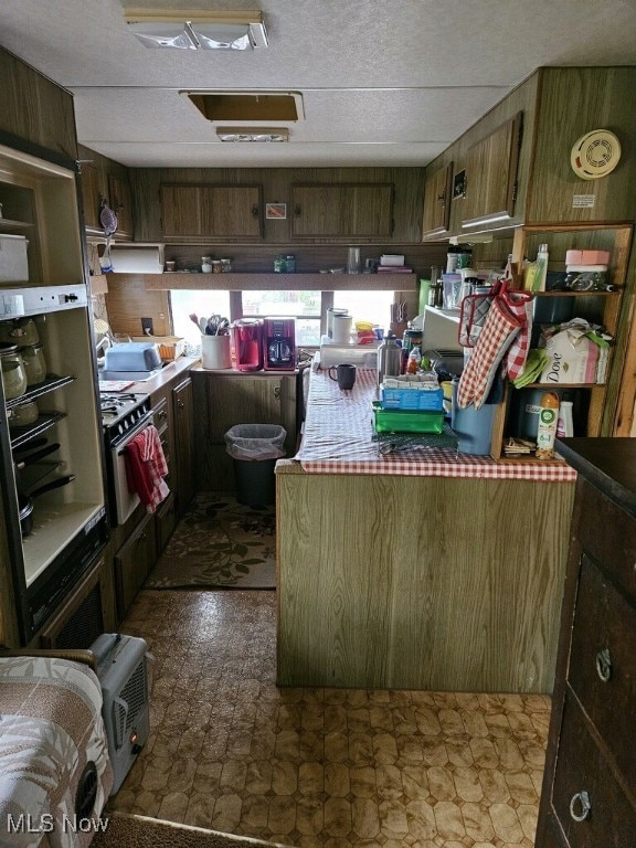 kitchen with wall oven, wooden walls, and dark floors