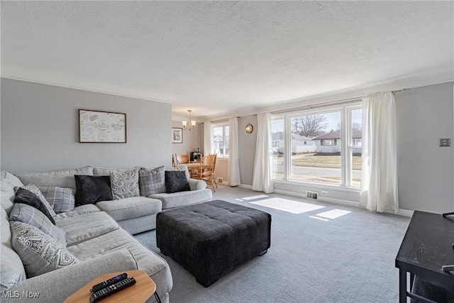 carpeted living room featuring baseboards, a notable chandelier, a textured ceiling, and visible vents