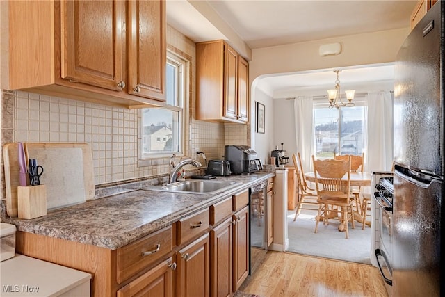 kitchen with tasteful backsplash, light wood-type flooring, freestanding refrigerator, gas stove, and a sink