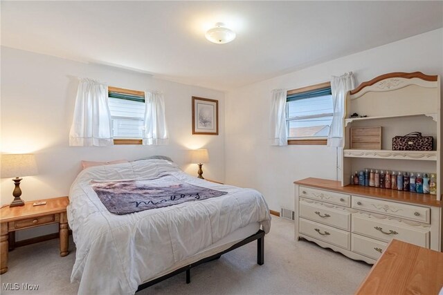 bedroom with visible vents, light carpet, and baseboards