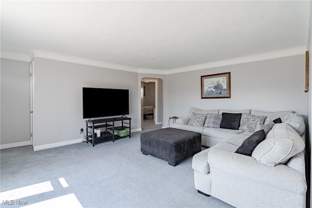 carpeted living area with arched walkways and baseboards