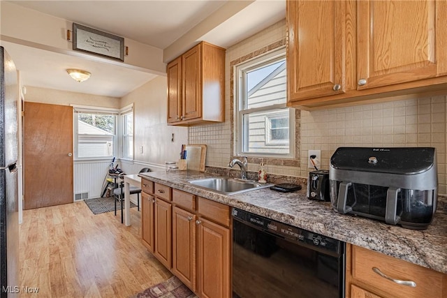 kitchen with tasteful backsplash, black appliances, light wood-style floors, and a sink