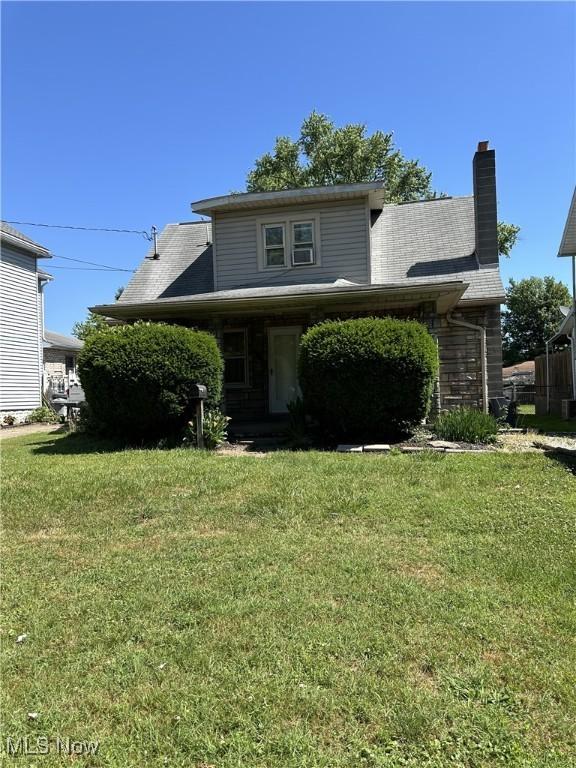 view of front of house featuring a chimney and a front yard