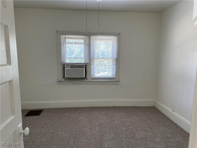 carpeted empty room with cooling unit, visible vents, and baseboards