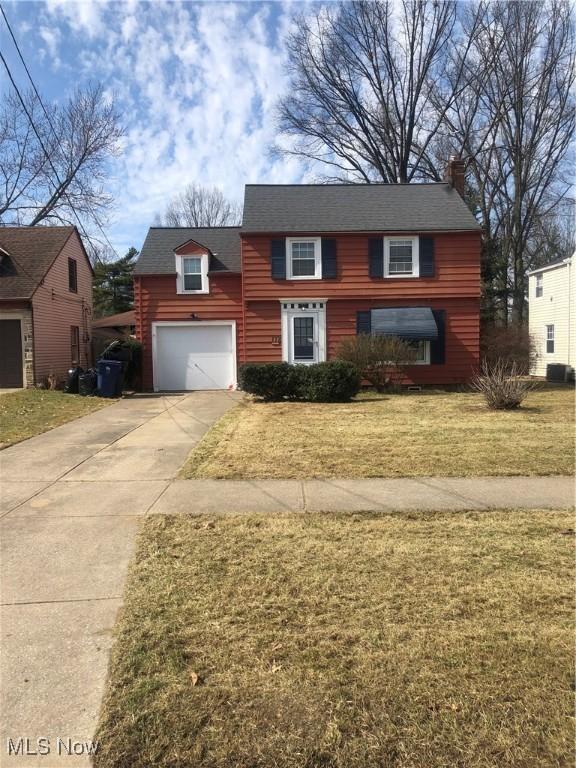 view of front of house featuring a garage, central air condition unit, concrete driveway, and a front lawn