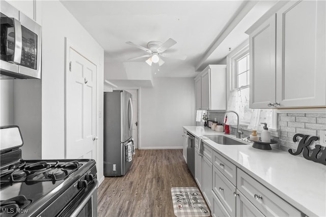 kitchen featuring a sink, backsplash, dark wood-style floors, stainless steel appliances, and light countertops