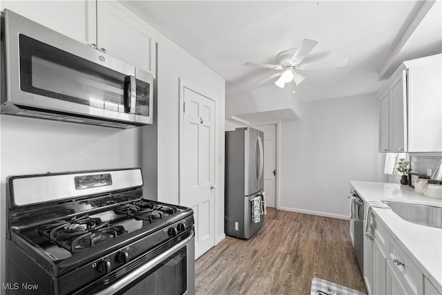 kitchen featuring wood finished floors, light countertops, appliances with stainless steel finishes, white cabinetry, and tasteful backsplash