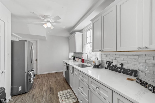 kitchen featuring a sink, backsplash, dark wood-style floors, stainless steel appliances, and light countertops