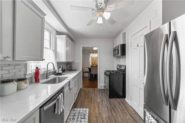 kitchen with a sink, light stone counters, backsplash, dark wood-style floors, and stainless steel appliances