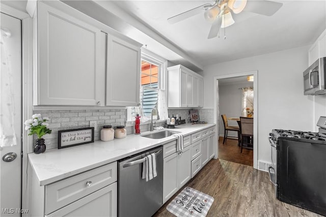 kitchen with dark wood-type flooring, decorative backsplash, stainless steel appliances, white cabinetry, and a sink