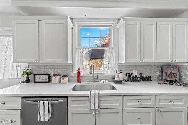 kitchen with white cabinets, dishwasher, light countertops, and a sink