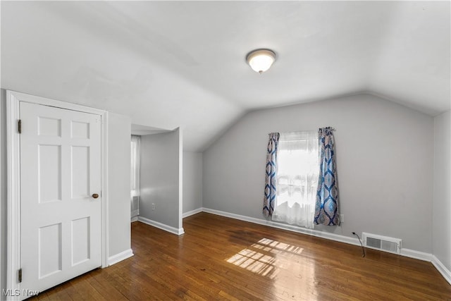 bonus room with visible vents, lofted ceiling, baseboards, and hardwood / wood-style floors