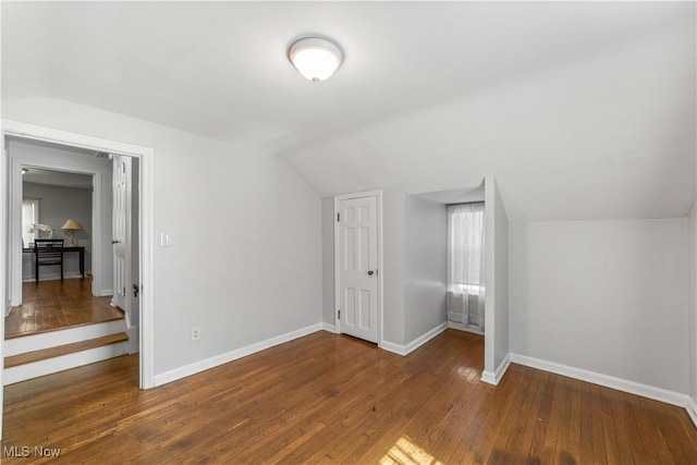 additional living space with vaulted ceiling, baseboards, and wood-type flooring