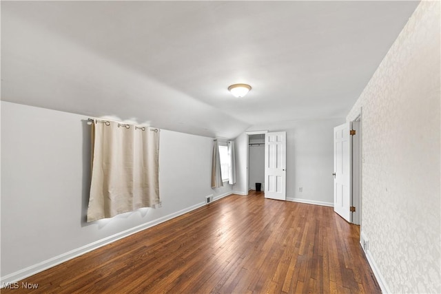 interior space featuring visible vents, a closet, wood-type flooring, baseboards, and vaulted ceiling