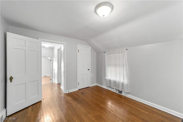 interior space with baseboards, lofted ceiling, and hardwood / wood-style floors