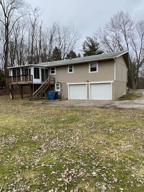 view of front of house featuring stairway, a wooden deck, driveway, a sunroom, and an attached garage