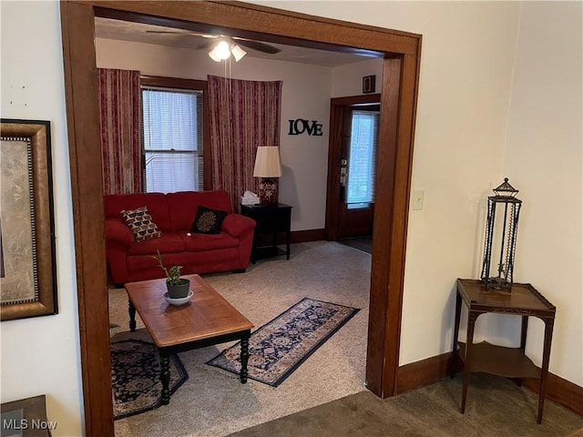 carpeted living area featuring baseboards and ceiling fan