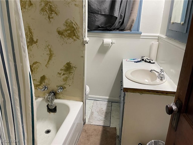 bathroom with baseboards, toilet, shower / bath combo, and vanity