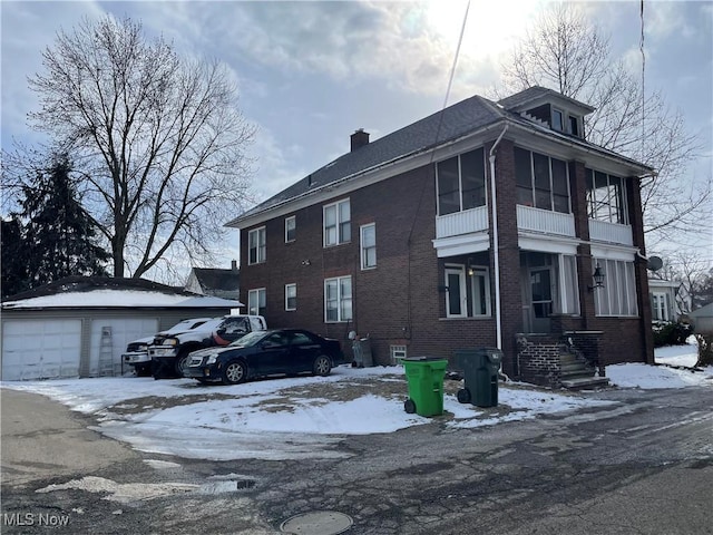 view of front of home featuring brick siding, a chimney, a detached garage, and an outdoor structure