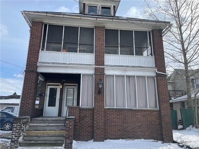 view of front of property featuring brick siding and a sunroom