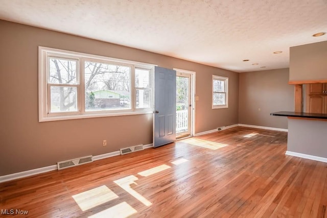 interior space featuring light wood-type flooring, visible vents, and baseboards