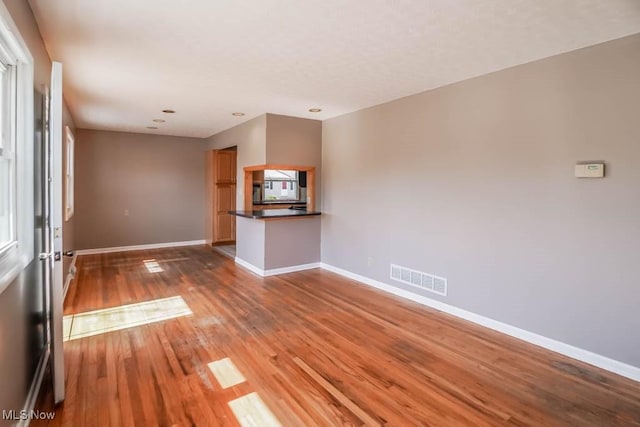 unfurnished living room with visible vents, baseboards, and wood finished floors