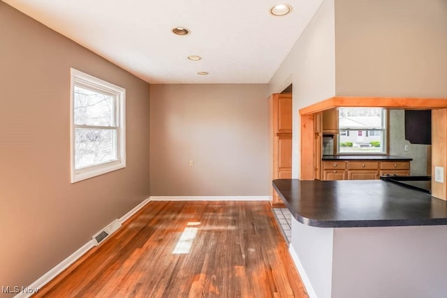 kitchen featuring dark countertops, visible vents, baseboards, and a wealth of natural light