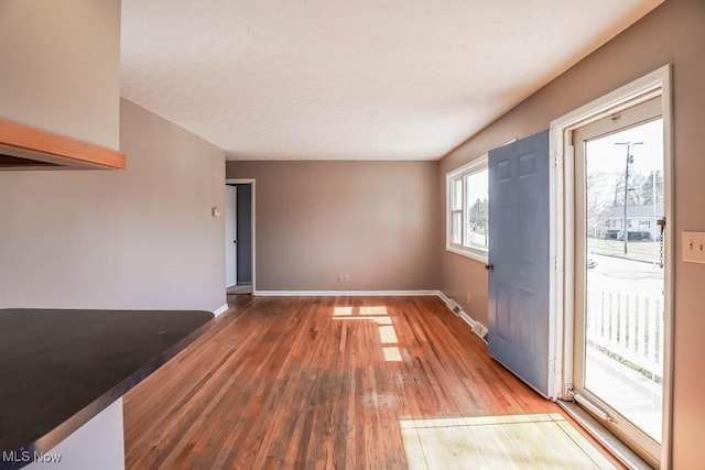 unfurnished living room with wood finished floors and baseboards