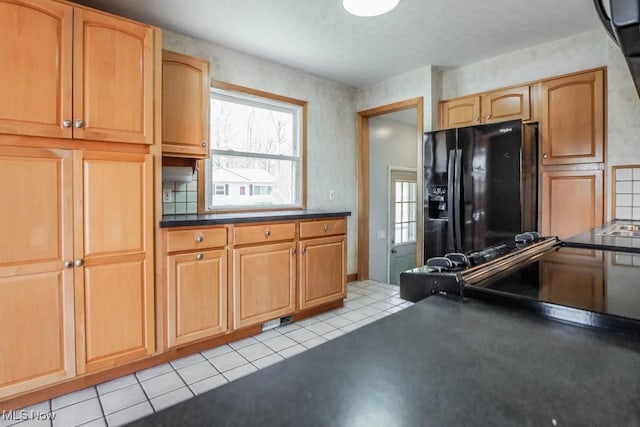 kitchen featuring light tile patterned floors, dark countertops, and black fridge