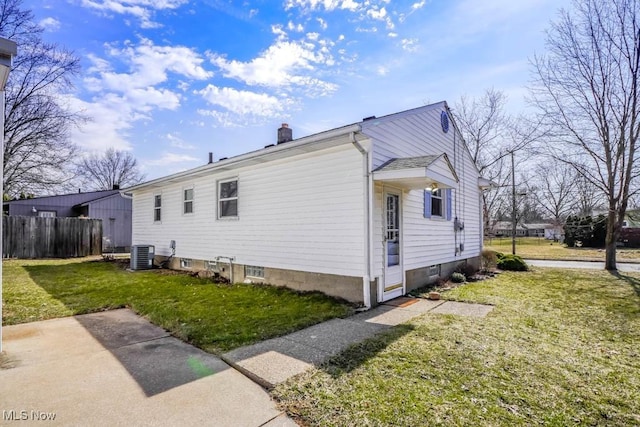 view of home's exterior with central AC unit, a chimney, a yard, and fence