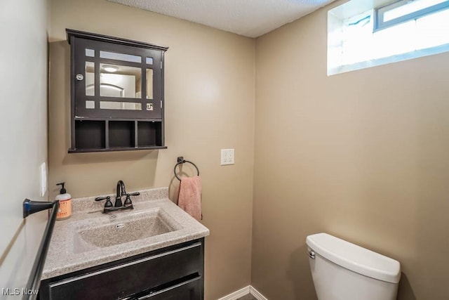 bathroom featuring toilet, vanity, and baseboards