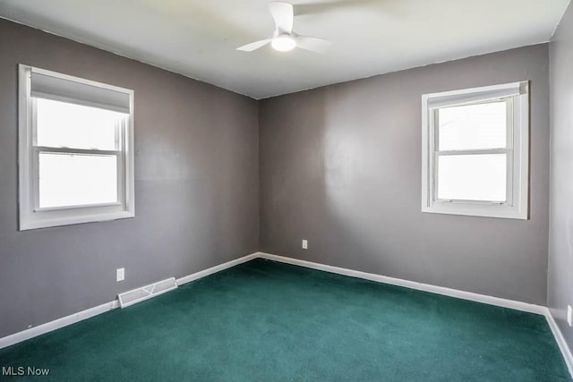 carpeted spare room with visible vents, baseboards, and a ceiling fan