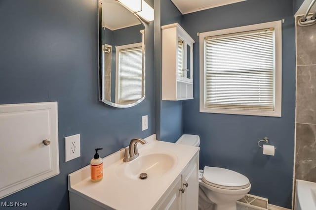 bathroom with vanity, baseboards, visible vents, a bathing tub, and toilet