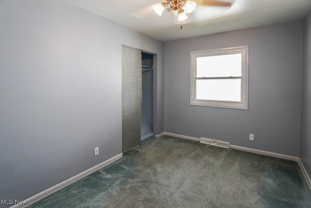 unfurnished bedroom featuring a ceiling fan, visible vents, baseboards, a closet, and dark carpet