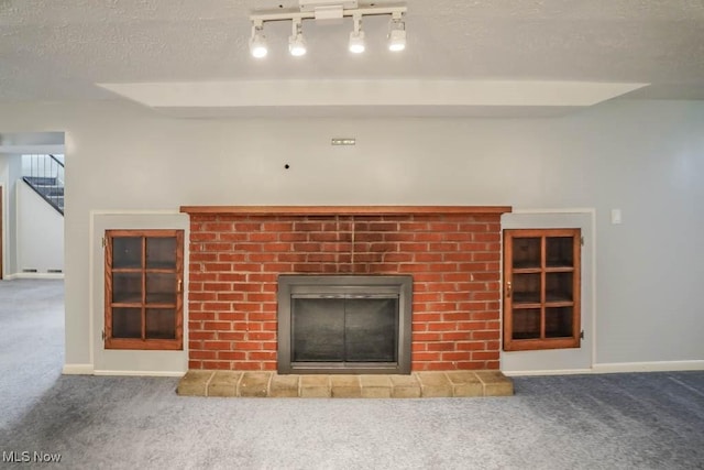 room details featuring a brick fireplace, carpet, baseboards, and a textured ceiling