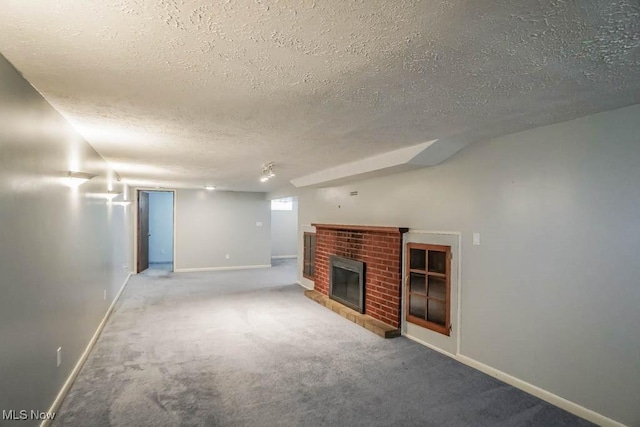 basement with a brick fireplace, carpet flooring, baseboards, and a textured ceiling