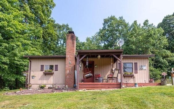 back of house featuring a yard and a chimney