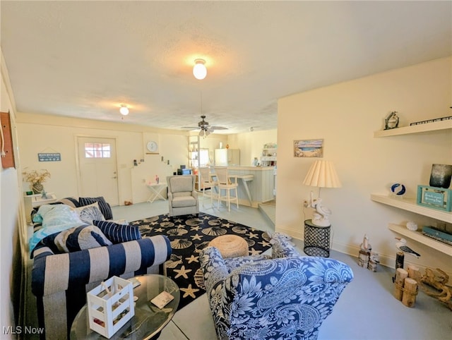 living area with baseboards and a ceiling fan