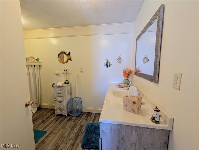 bathroom featuring vanity, wood finished floors, baseboards, and a textured ceiling