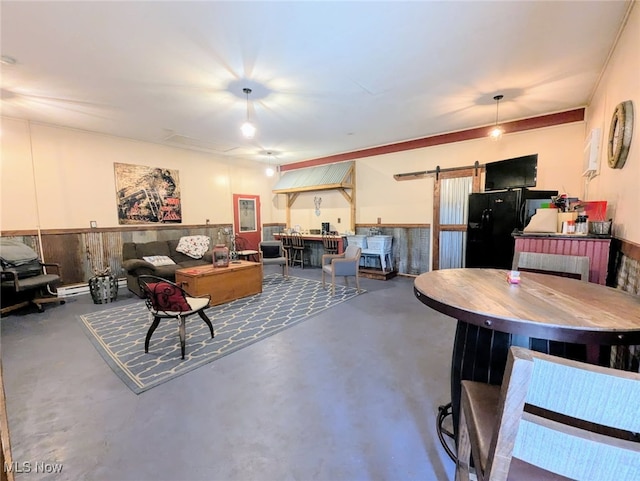 interior space featuring a baseboard heating unit, a barn door, a wainscoted wall, and concrete floors