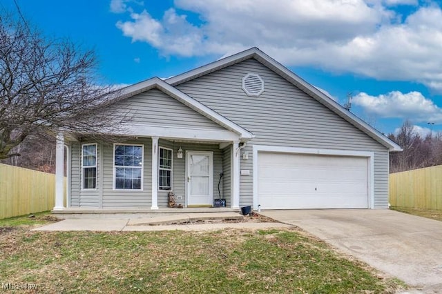 view of front facade with concrete driveway, an attached garage, and fence