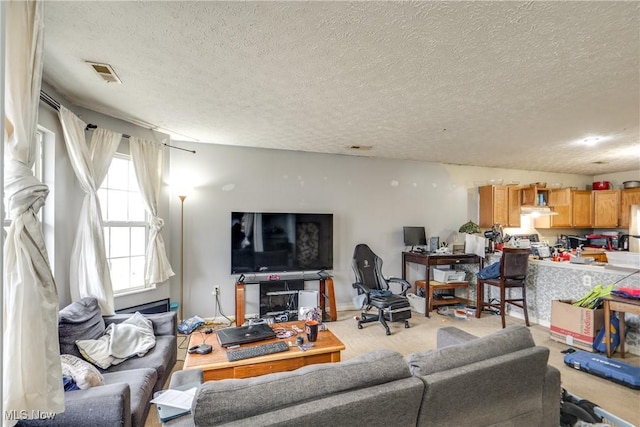 living room with a textured ceiling, visible vents, and light carpet