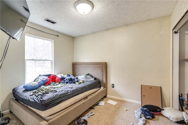 bedroom with visible vents, carpet flooring, a textured ceiling, and baseboards