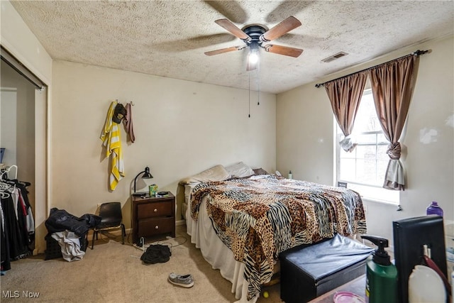 bedroom featuring visible vents, carpet floors, a textured ceiling, and a ceiling fan