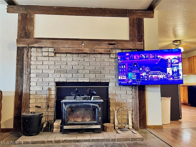 room details featuring a wood stove, a ceiling fan, and a textured ceiling