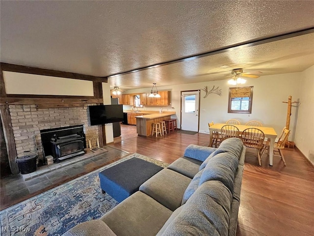 living room featuring a ceiling fan, wood finished floors, baseboards, and a textured ceiling